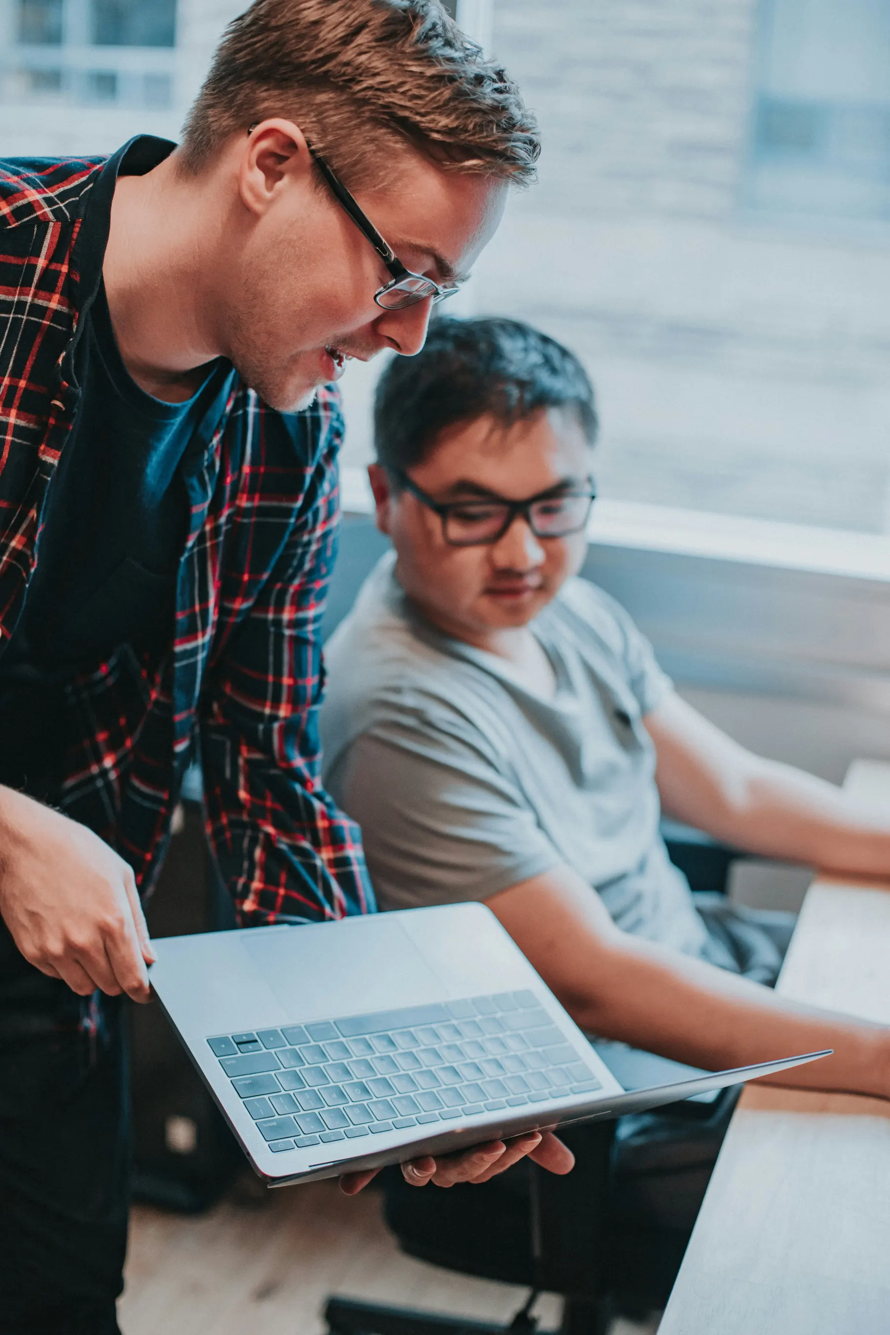 Two people reviewing work together on a laptop.