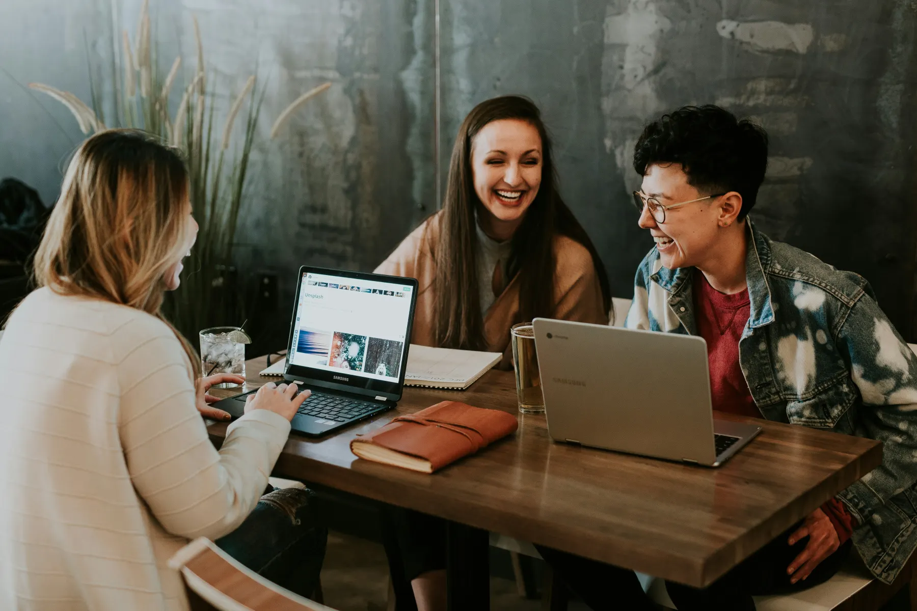 Three colleagues gathered around laptops during a planning conversation.