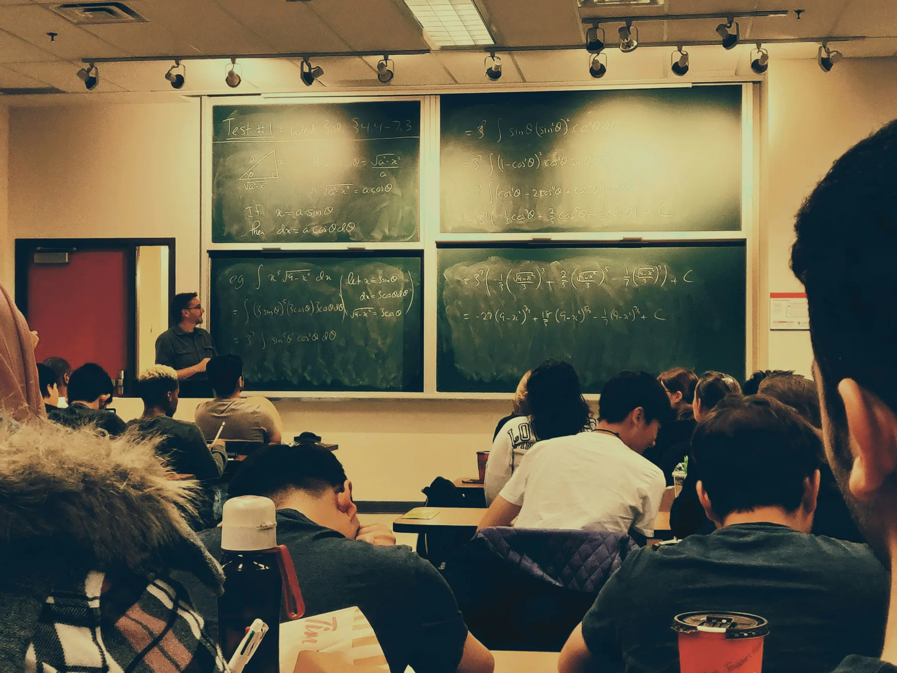 A student seated in front of a chalkboard.