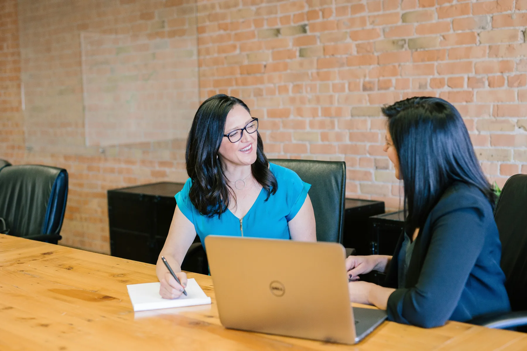 Two program staff members reviewing work together at a laptop.